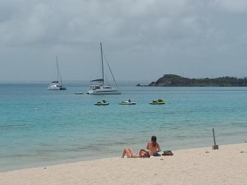 two people laying on the beach with boats in the water at Smart-lidays SXM in Grand Case