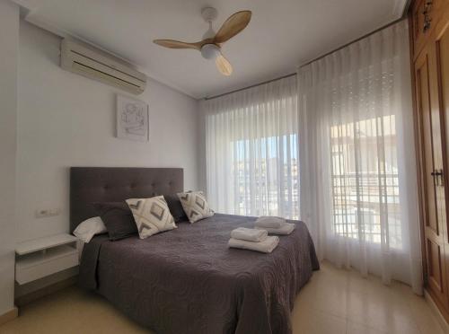 Un dormitorio con una cama y un ventilador de techo. en Adosado con piscina al lado de la playa, en Santa Pola