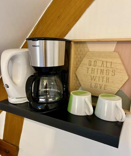une cafetière et deux tasses sur une étagère dans l'établissement Les gîtes du Mesnil chambre standard, à Équemauville