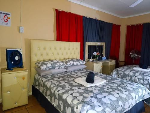 a bedroom with two beds and a television and red curtains at Angelina Victoria Overnight in Colesberg