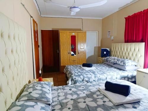 two beds in a room with red curtains at Angelina Victoria Overnight in Colesberg