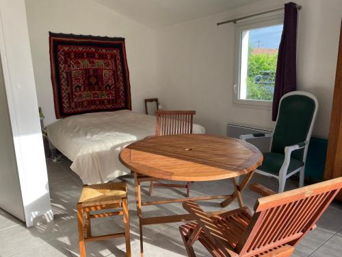 une pièce avec une table, des chaises et un lit dans l'établissement Un studio indépendant avec jardin, à Talmont-Saint-Hilaire