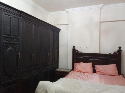 a bedroom with a bed with a black headboard and pink pillows at عماره 7 ج in Cairo