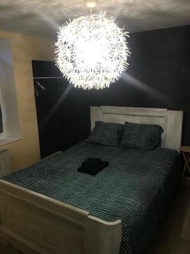 a bedroom with a bed with a large chandelier at Gite de la Croix in Briantes