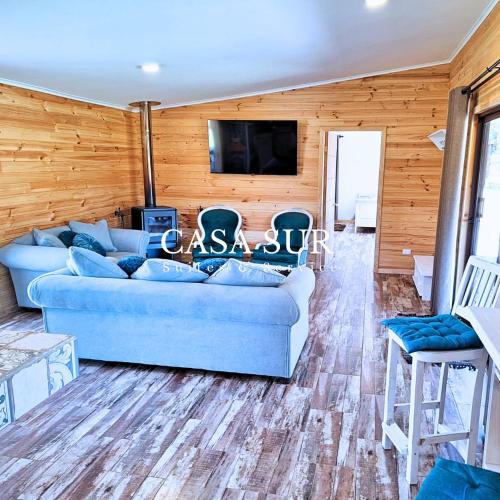 a living room with a blue couch and a tv at La Casa del Bosque in Neltume