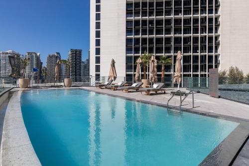 a swimming pool with chairs and umbrellas in front of a building at Simply Comfort Vacation Homes Rental Apartments at Nobles Tower Luxury Burj View in Dubai