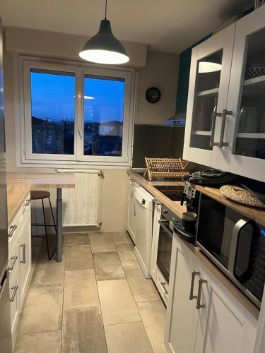 - une cuisine avec des placards blancs, une table et 2 fenêtres dans l'établissement Apartment T3, à Billère