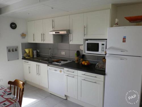 une cuisine avec des armoires blanches et un réfrigérateur blanc dans l'établissement Duplex Eden Park, au Pradet