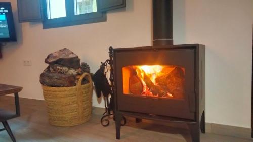 a wood burning stove in a room with a basket at La Casa de mi Tía María in Cortelazor