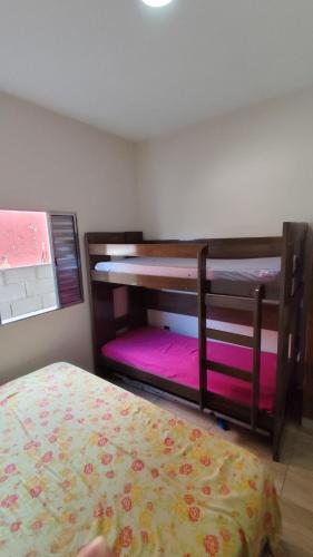 a bedroom with two bunk beds with pink sheets at Descanso - Casa de Praia in Mongaguá