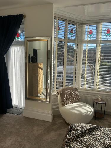 a room with a mirror and a chair and windows at The Magnolia in Rhôs-on-Sea