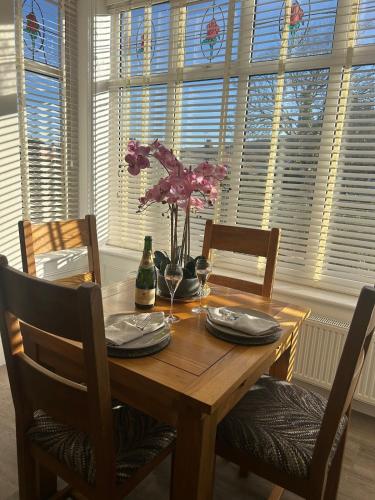 a wooden table with chairs and a table with flowers on it at The Magnolia in Rhôs-on-Sea