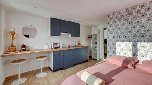 a bedroom with a bed and a kitchen with blue cabinets at Le Littoral - Appart'Escale in Saint-Nazaire