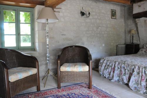 - une chambre avec deux chaises, un lit et une lampe dans l'établissement Les Berthiers - région des châteaux et des vignes, à Sepmes