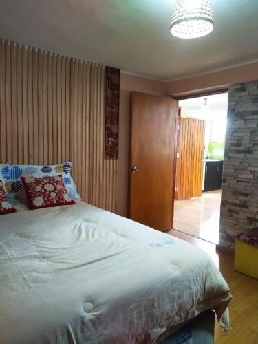 a bedroom with a large white bed and a wooden door at Samay Wasi in Ayacucho