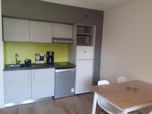 una cucina con mobili bianchi e un tavolo di Appartement 30m2 avec jardin et piscine chauffée à La Palmeraie Grimaud a Grimaud
