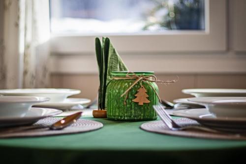 a table with white plates and a green container with a tree decoration at Chata Idylka - Nová chata se zahradou in Loučná nad Desnou