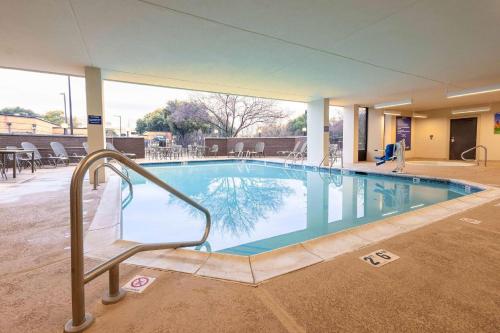 a large swimming pool with a handrail in a hotel at Heritage Inn Suites Houston Sugar Land, Trademark by Wyndham in Sugar Land