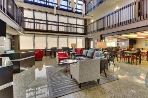 a lobby with tables and chairs and a restaurant at Heritage Inn Suites Houston Sugar Land, Trademark by Wyndham in Sugar Land