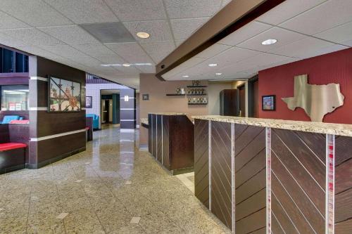 an office lobby with a reception counter and red walls at Heritage Inn Suites Houston Sugar Land, Trademark by Wyndham in Sugar Land