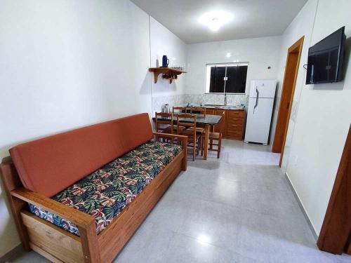a living room with a couch and a kitchen at Pousada Pegadas na Areia in Palhoça