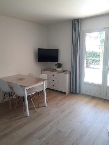 un salon avec une table et une télévision dans l'établissement Appartement 30m2 avec jardin et piscine chauffée à La Palmeraie Grimaud, à Grimaud