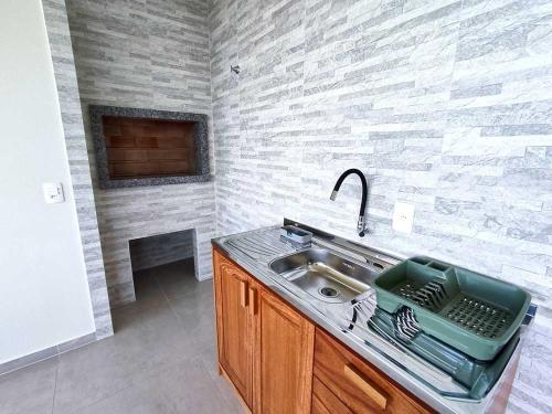 a kitchen with a sink and a fireplace at Pousada Pegadas na Areia in Palhoça