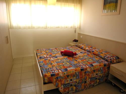 a bedroom with a bed with a red stuffed animal on it at Appartamenti Ai Pini in Bibione