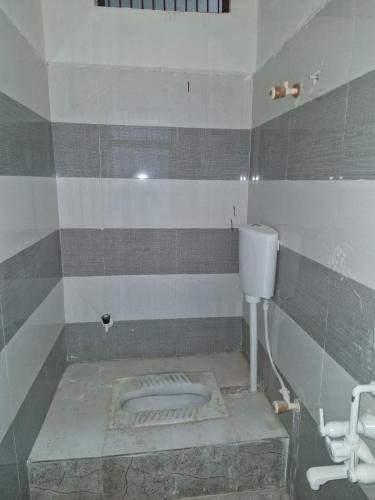 a bathroom with a toilet and a sink in it at Triveni Darshan Homestay in Jhūsi