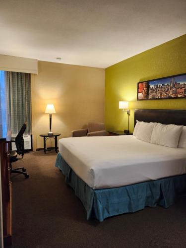 a hotel room with a large bed and a couch at Heritage Inn Suites Houston Sugar Land, Trademark by Wyndham in Sugar Land