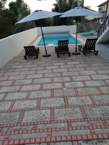 a group of chairs and umbrellas next to a pool at Catloc & Kitcat Alojamento Local in Costa de Além