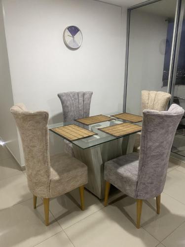 a dining room table with chairs and a clock on the wall at Apartamento Amoblado de Lujo en Cucuta in Cúcuta