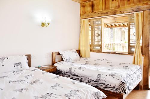 two beds in a room with a window at Tourist Courtyard Hotel in Jianchuan