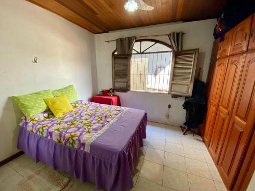 a bedroom with a bed with purple sheets and a window at Casa lindíssima para a Cop30 in Belém