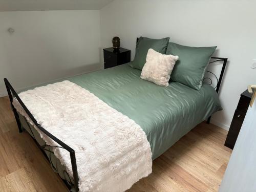 - un lit avec des draps et des oreillers verts et blancs dans l'établissement Appart Sofia uckange, à Uckange