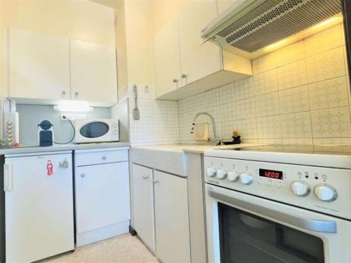 une cuisine avec des armoires blanches et un four à plaques de cuisson dans l'établissement Gréoux-les-bains Studio fonctionnel proche thermes, à Gréoux-les-Bains