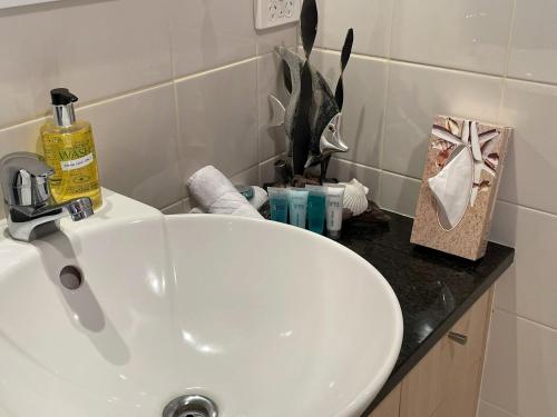 a white sink in a bathroom with a black counter at Ocean Breeze Resort Pauanui in Pauanui