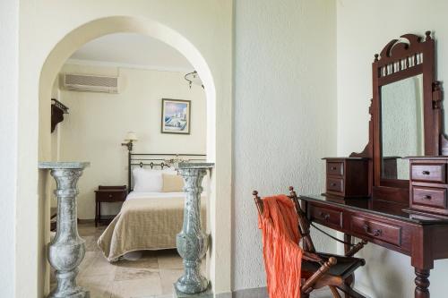 a bedroom with a bed and a desk and a mirror at Contaratos Beach Hotel in Naousa