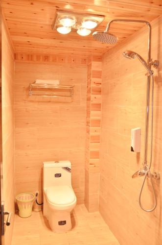 a bathroom with a toilet and a shower at Tourist Courtyard Hotel in Jianchuan
