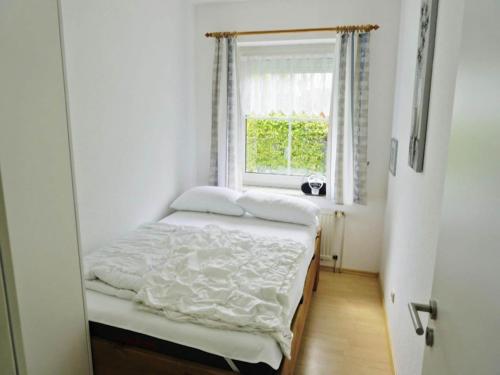 a small bedroom with a bed and a window at Ferienwohnung im Erdgeschoss in Neßmersiel in Neßmersiel