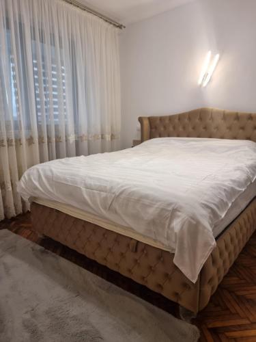 a bedroom with a large bed with white sheets at 8 MAI Residence in Târgu Jiu