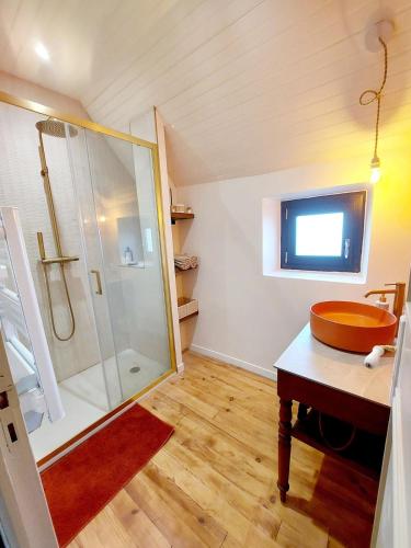 La salle de bains est pourvue d'une douche, d'un lavabo et d'une télévision. dans l'établissement Grange rénovée avec vue dans village paisible, à Pruines