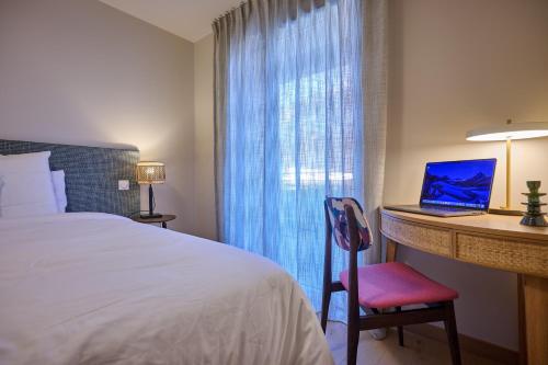 a hotel room with a bed and a desk with a laptop at Le Miroir De Saint-Jacques in Sallanches