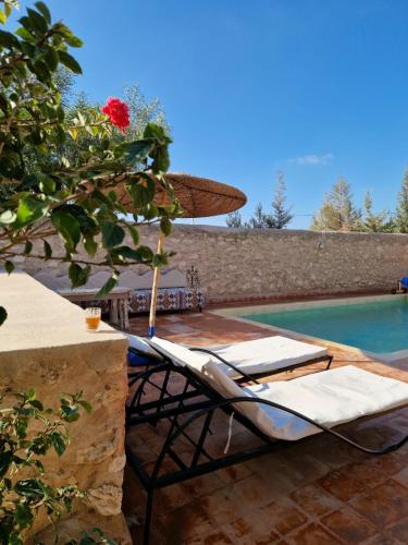 una piscina con 2 tumbonas, una sombrilla y una piscina en Dar Anouar, en Sidi Kaouki