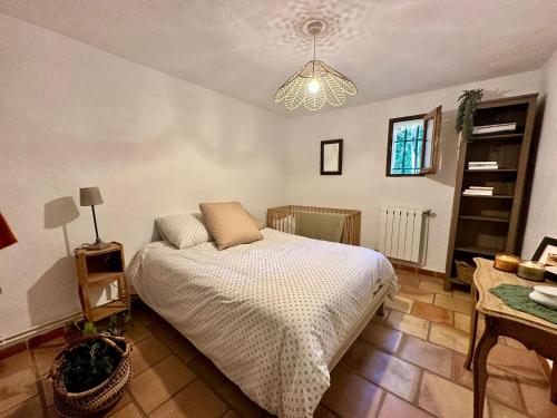 a bedroom with a bed and a chandelier at Rez de jardin au calme dans le parc des calanques in La Ciotat