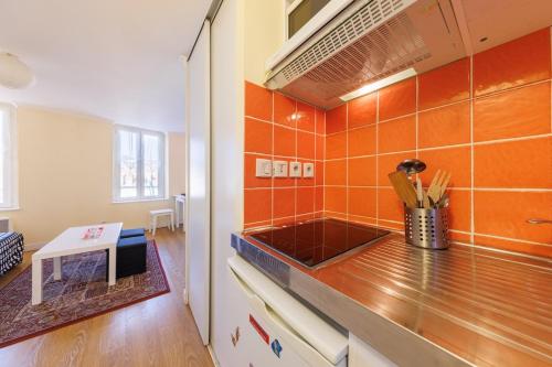 - une cuisine avec du carrelage orange sur le mur dans l'établissement Le Duplex, Confort et style pour un séjour parfait, à Chamalières