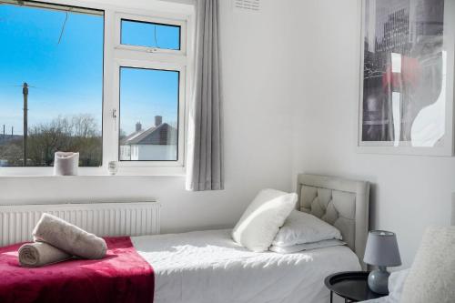 a bedroom with a bed with a red blanket and a window at Disc-counts For Family & Work stays, Coffee machine - Fast wifi - Free parking - Private Garden in Borehamwood