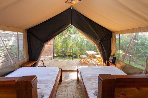 two beds in a tent with a table and chairs at Kivulini Eco Park Karen in Nairobi