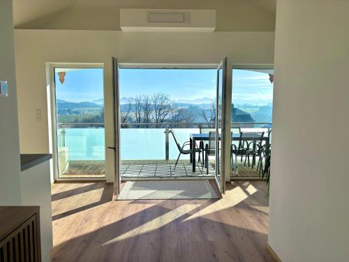 a room with a door open to a balcony with a table at Gästehaus Seeblick Penthousewohnung in Seekirchen am Wallersee
