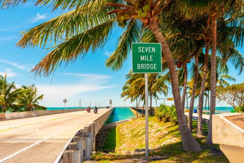 a sign on a road next to a beach with palm trees at Glunz Ocean Beach Hotel and Resort in Marathon